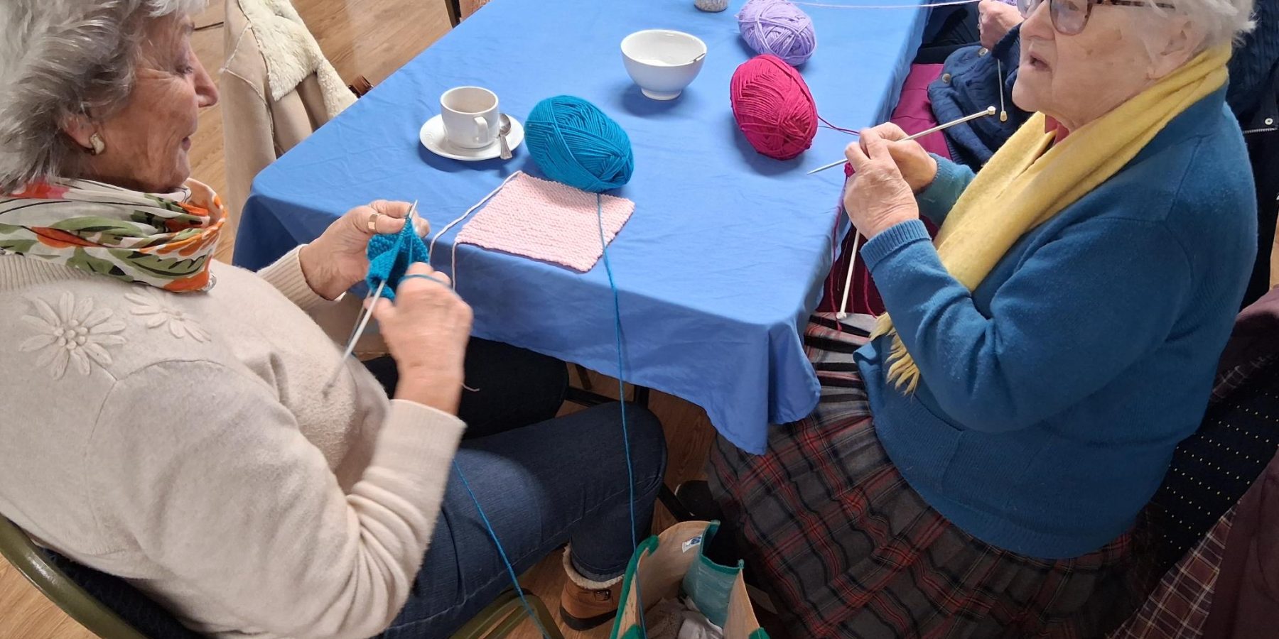 A volunteer and attendee at the Hub&Grub knitting together